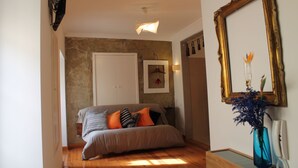 Ein Schlafzimmer mit einem Bett, einem Wandfernseher, einem gerahmten Spiegel und einer Vase mit Blumen.