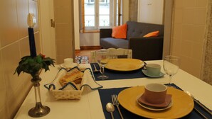 Ein Esstisch ist mit Tellern, Tassen und einer Blumenvase gedeckt.