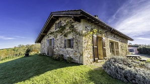 A stone house with a sloped roof, wooden shutters, and a well-maintained lawn. - Sheepfold in the village of Sare (Sare)