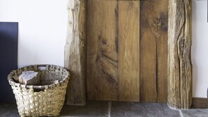 A rustic wooden door with a simple latch, a woven basket on the floor, and a stone wall. - Sheepfold in the village of Sare (Sare)
