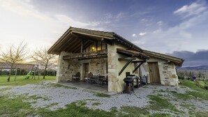 A rustic stone building with a sloped roof, outdoor seating, and a barbecue area. - Sheepfold in the village of Sare (Sare)