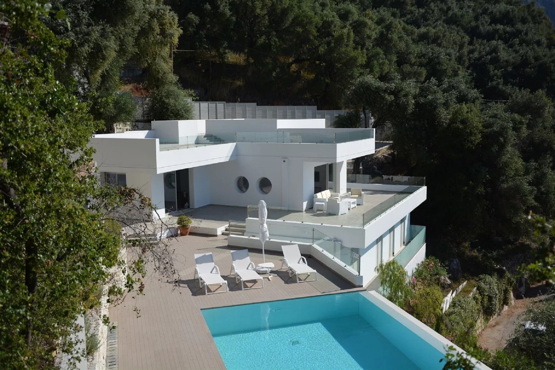 A modern two-story house with a rooftop pool and outdoor seating area.