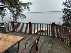 Um deck de madeira com mesa e cadeiras, com vista para um corpo de água.