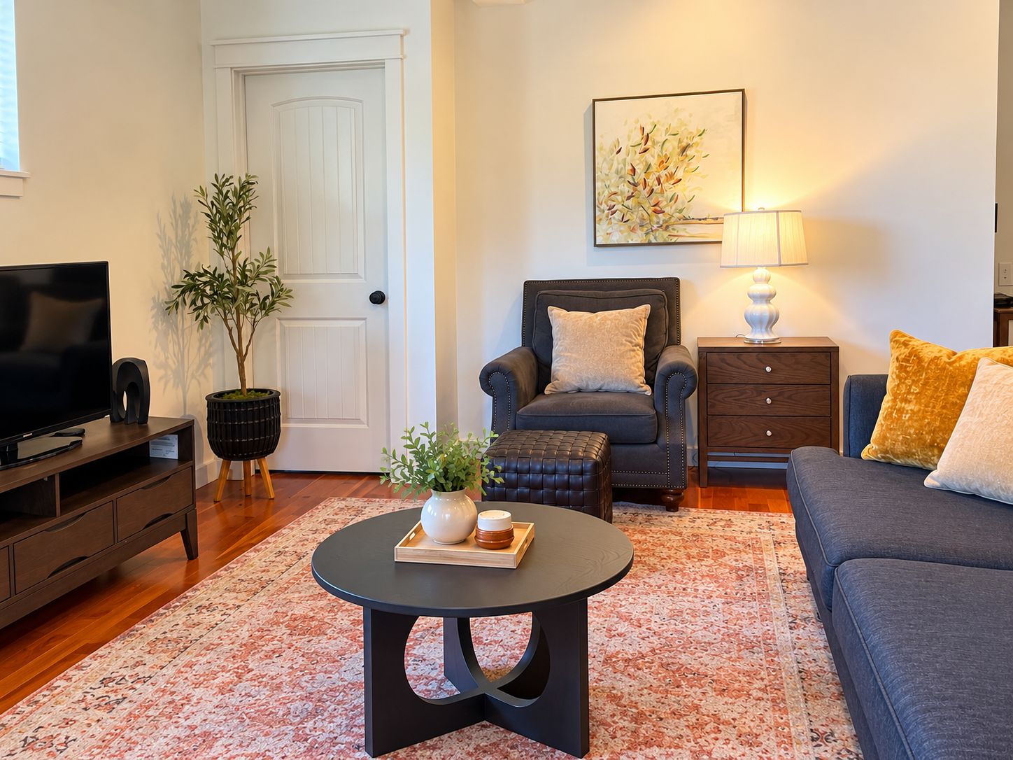 Un salon comprenant un téléviseur, un canapé, un fauteuil, une table basse et une lampe.
