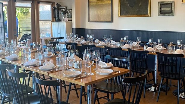 A dining area with multiple tables set for service, chairs, and a view of the outdoors.