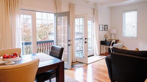 A spacious living room with a dining area, large sliding glass doors leading to a balcony, and a view of the outside.