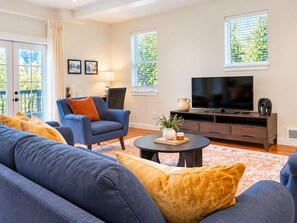 Una sala de estar con sofá, sillón, televisión y una mesa de centro.