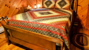 A wooden-paneled room with a bed featuring a quilted bedspread. -  Convenient to downtown Asheville,  Biltmore Estate, and Blue Ridge Pky.   (Asheville)