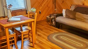 A cozy room with a wooden floor, a dining table with chairs, a sofa, a lamp, and a painting on the wall. -  Convenient to downtown Asheville,  Biltmore Estate, and Blue Ridge Pky.   (Asheville)