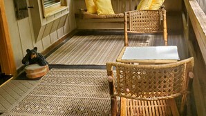 A cozy room with a wicker chair, a bench with yellow cushions, and a bear figurine on a rug. -  Convenient to downtown Asheville,  Biltmore Estate, and Blue Ridge Pky.   (Asheville)