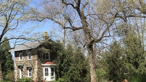 Ein Haus aus Stein mit rotem Dach, umgeben von einem gepflegten Garten und Bäumen.
