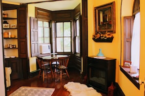 A dining area with a wooden table and chairs, a fireplace, and a large window with multiple panes.