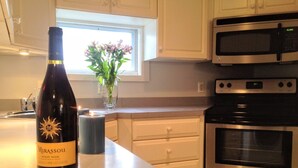 Une cuisine avec une bouteille de vin, une bougie et un vase rempli de fleurs sur le comptoir.