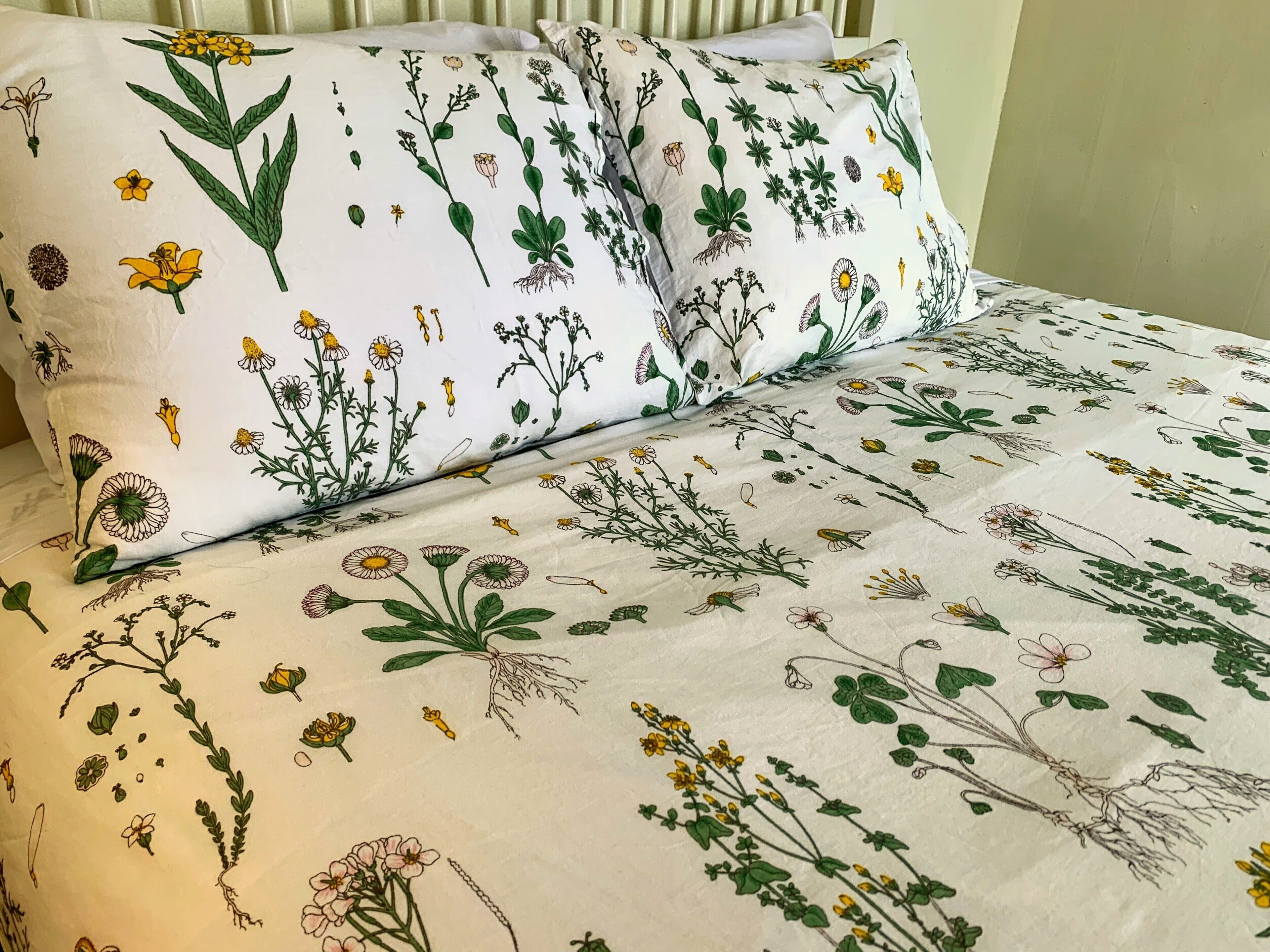 Cama com colcha e travesseiros estampados com motivos florais.