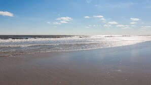 Une plage avec un ciel dégagé et des vagues calmes.