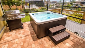 Een hottub met een houten terras, een barbecue en uitzicht op een jachthaven.