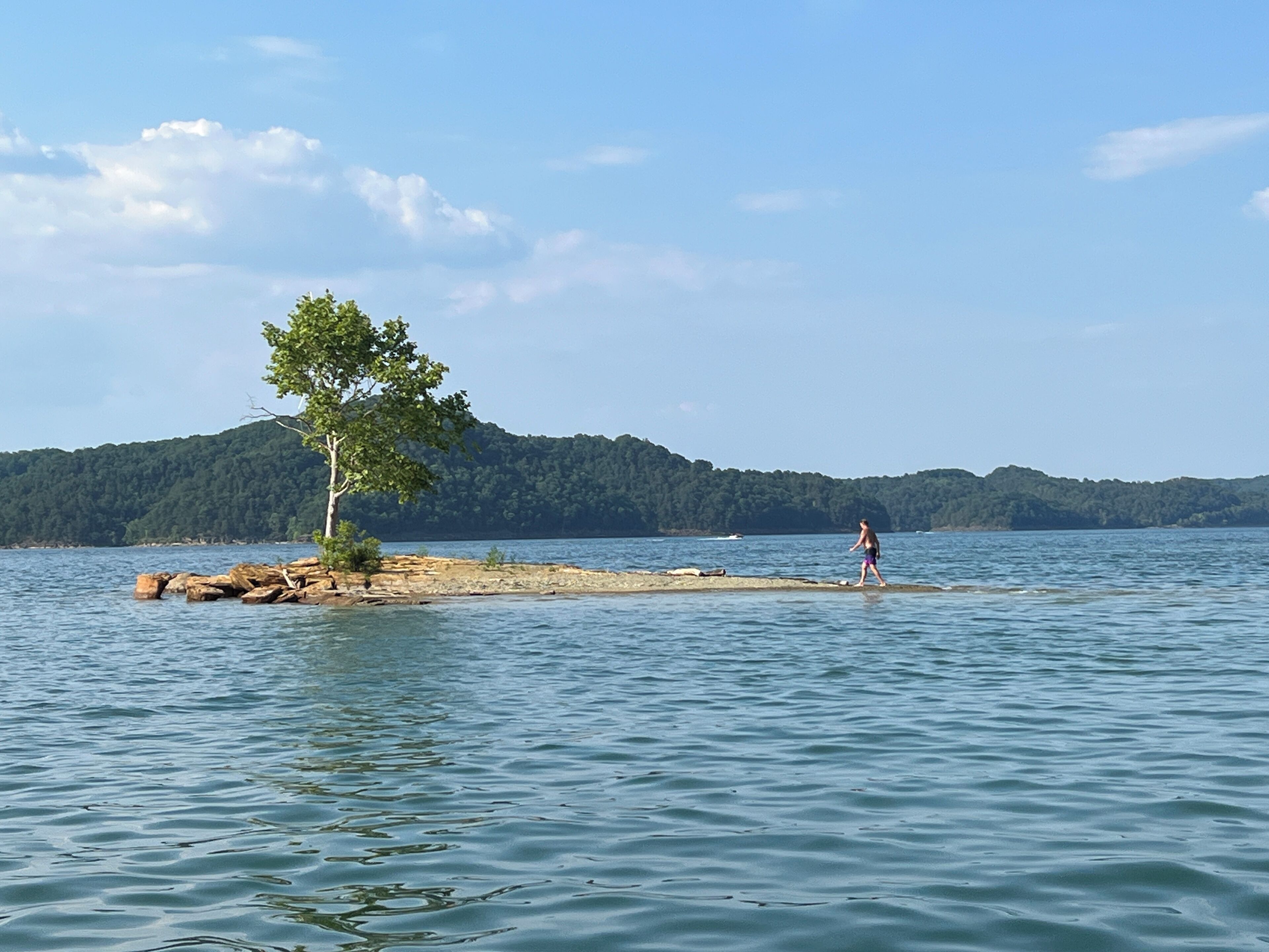 Un lac avec une petite île et une personne qui s’y promène.