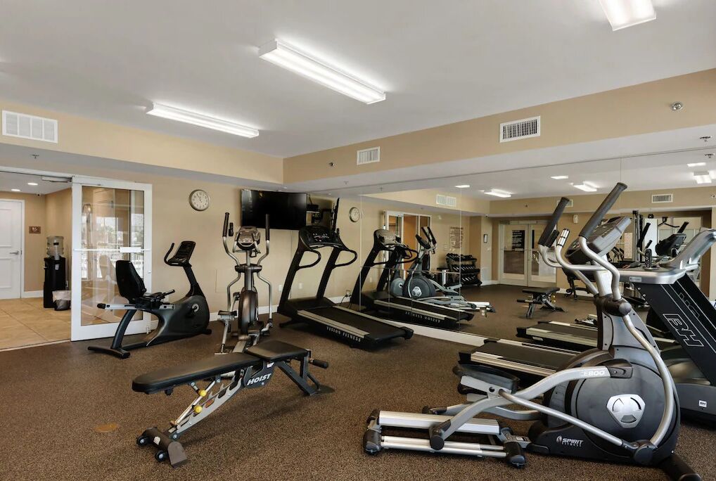 Une salle de sport équipée de tapis de course, de vélos elliptiques et de bancs de musculation.