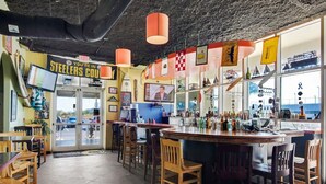 A bar with a counter, wooden chairs, and a television screen.
