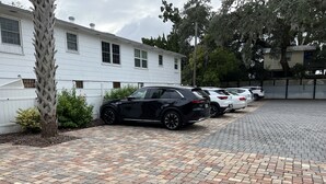 A parking area with a paved walkway, a white building, and several parked cars. - C6, Romantic apartment in city center, Flagler location, near beaches, parking! (St Augustine)