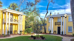 A yellow building with a covered porch and a brick pathway. - C6, Romantic apartment in city center, Flagler location, near beaches, parking! (St Augustine)