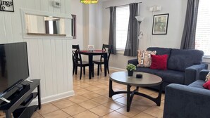 A living room with a TV, a dining table, and a sofa. - C6, Romantic apartment in city center, Flagler location, near beaches, parking! (St Augustine)