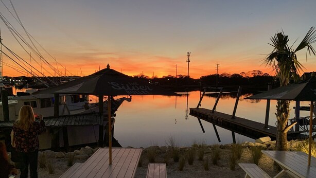 A waterfront restaurant with outdoor seating and a view of the sunset over the water. - C6, Romantic apartment in city center, Flagler location, near beaches, parking! (St Augustine)