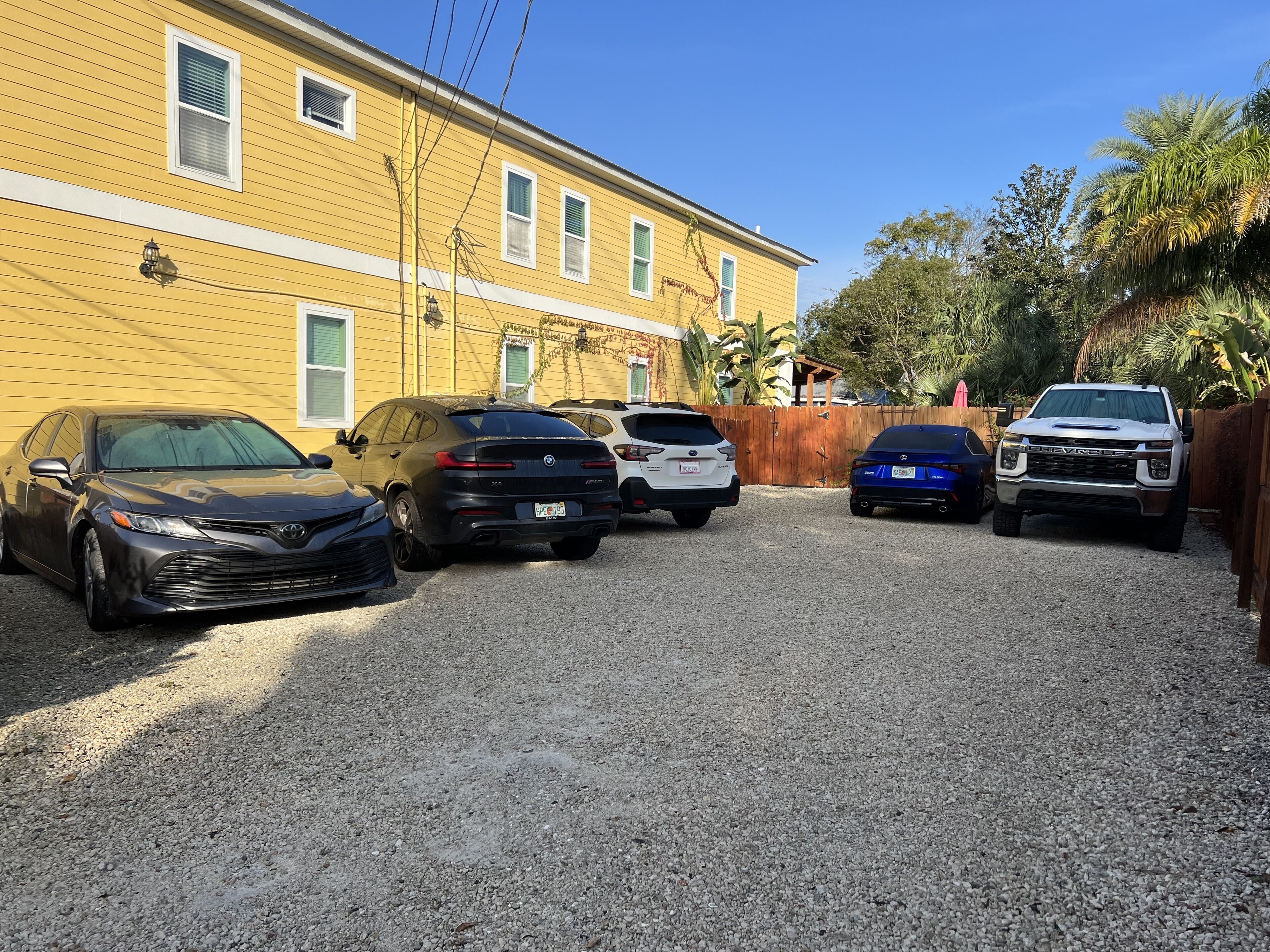 A parking area with multiple cars parked in front of a yellow building.