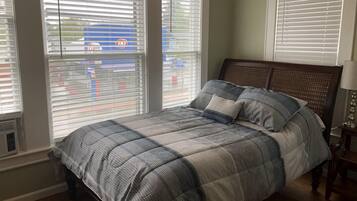 Una camera da letto con un letto, un comodino e una finestra con persiane.