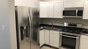 A compact kitchen with stainless steel appliances, white cabinets, and a tiled floor. - 1st Class Rentals Munson Manor VI at Chestnut 2nd Floor (Oneonta)