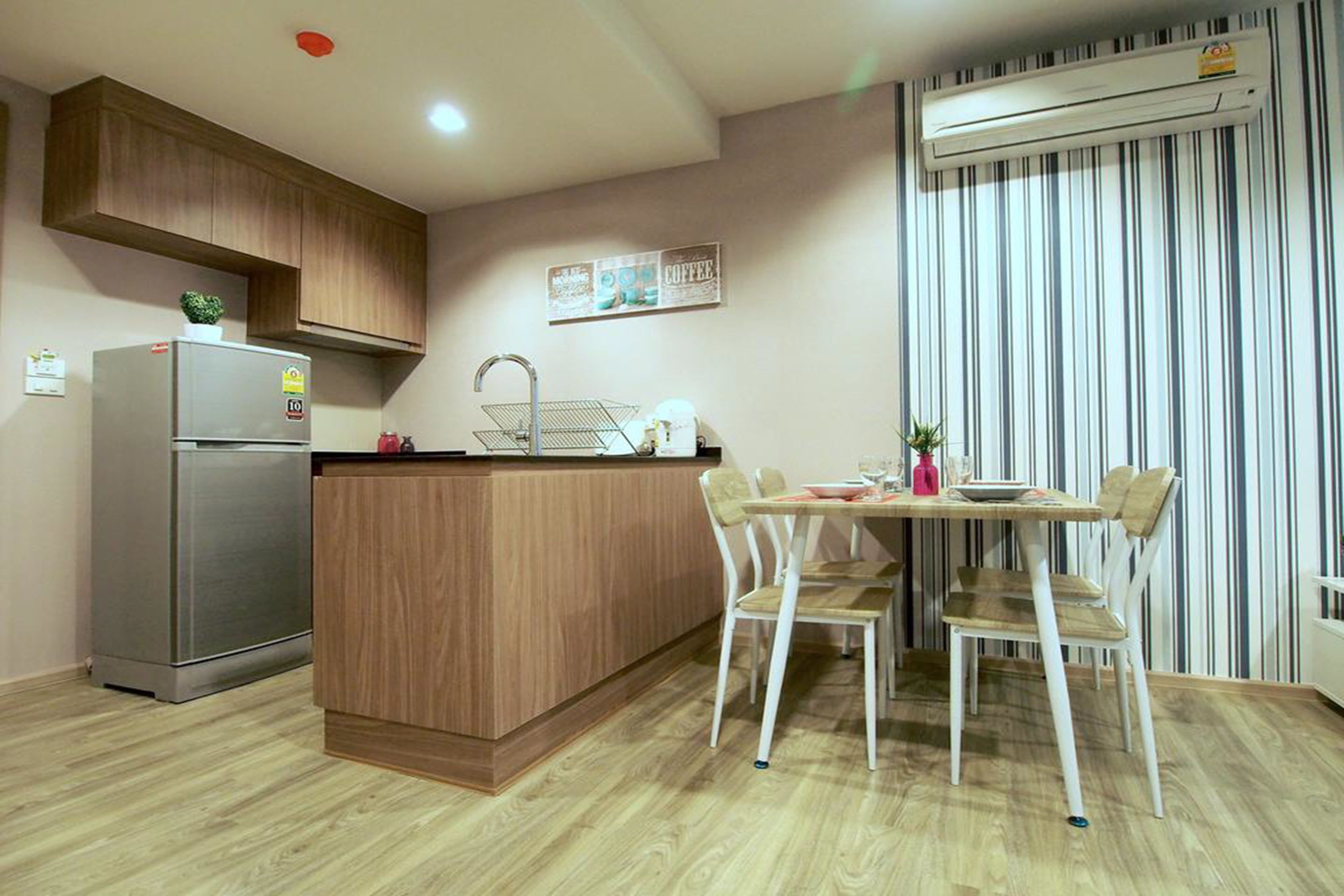 Una cocina moderna con una isla integrada, refrigerador de acero inoxidable y un comedor con sillas blancas.