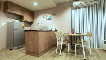 Una cocina moderna con una isla integrada, refrigerador de acero inoxidable y un comedor con sillas blancas.