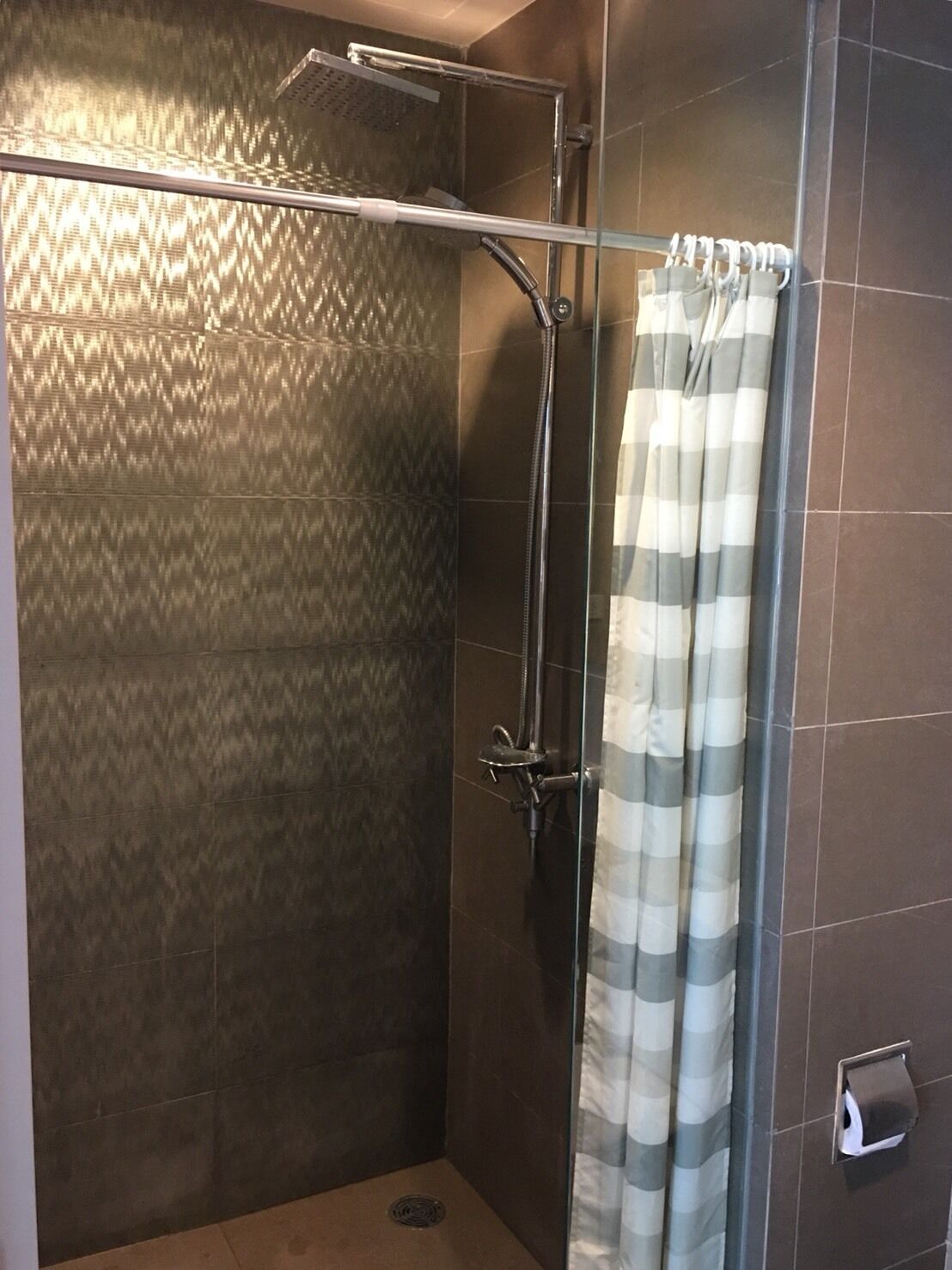 A shower area with a glass door, a showerhead, and a towel rack.