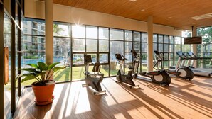 Ein Fitnessstudio mit Trainingsgeräten, großen Fenstern und einem Blumentopf.
