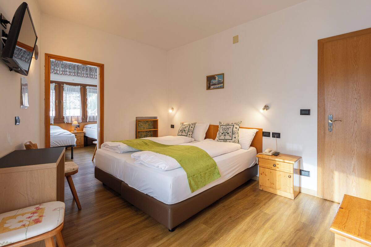 A well-lit bedroom with a large bed, bedside tables, a desk, and a chair.