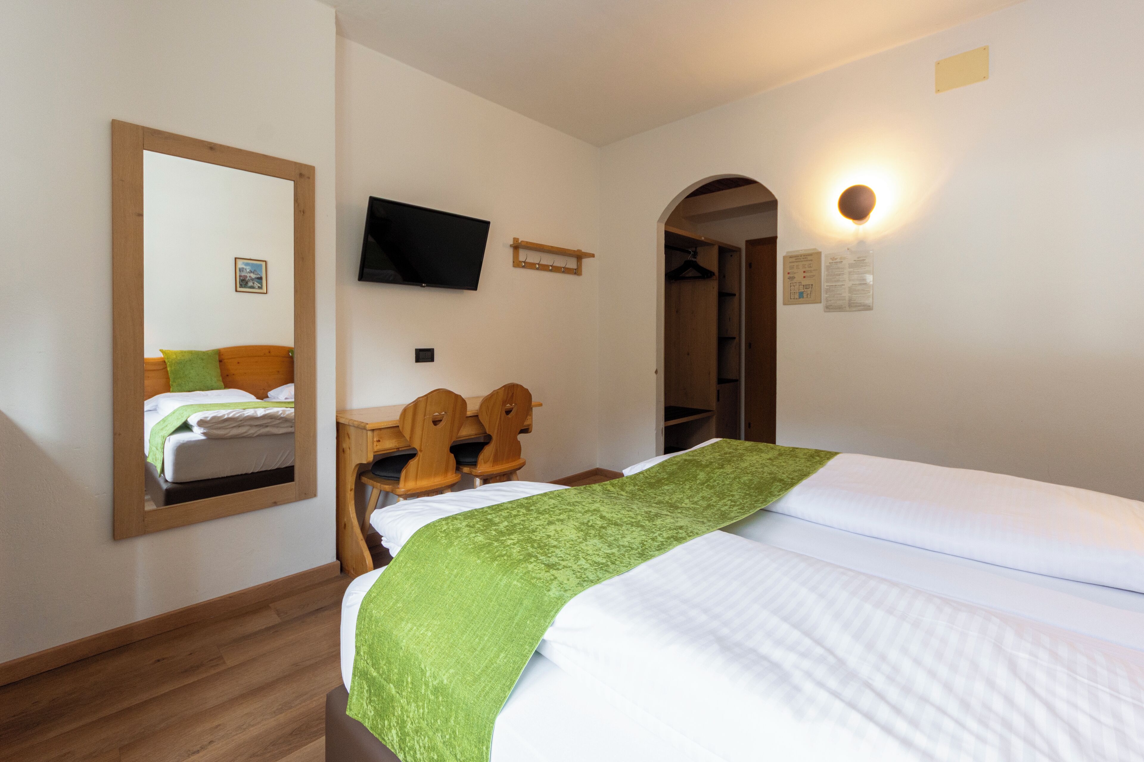 Hotelkamer met een bed, een houten hoofdeinde, een aan de muur bevestigde televisie en een kapstok.