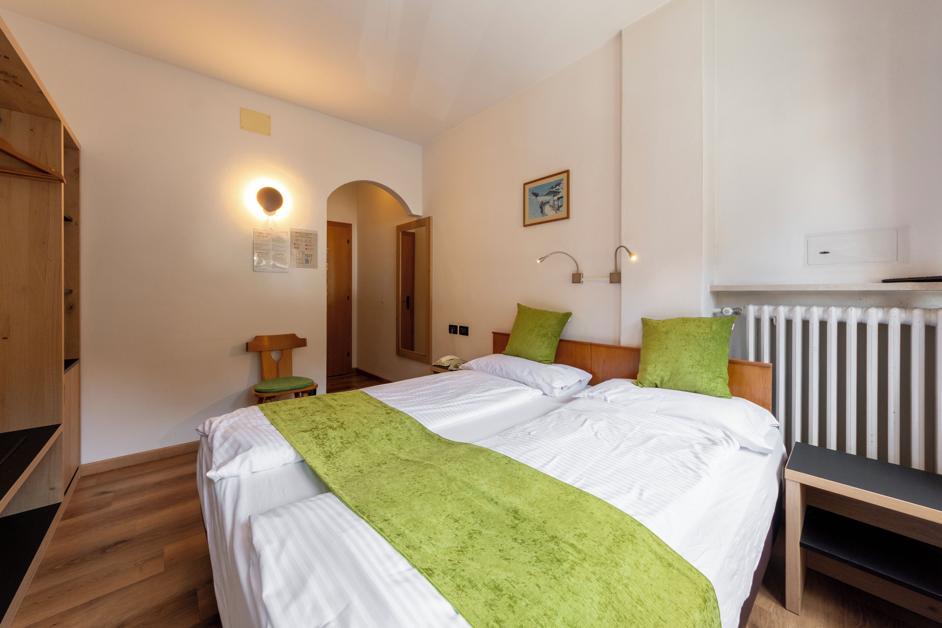 Ein Schlafzimmer mit Bett, Nachttisch, Lampe und Heizkörper.