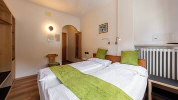 Ein Schlafzimmer mit Bett, Nachttisch, Lampe und Heizkörper.