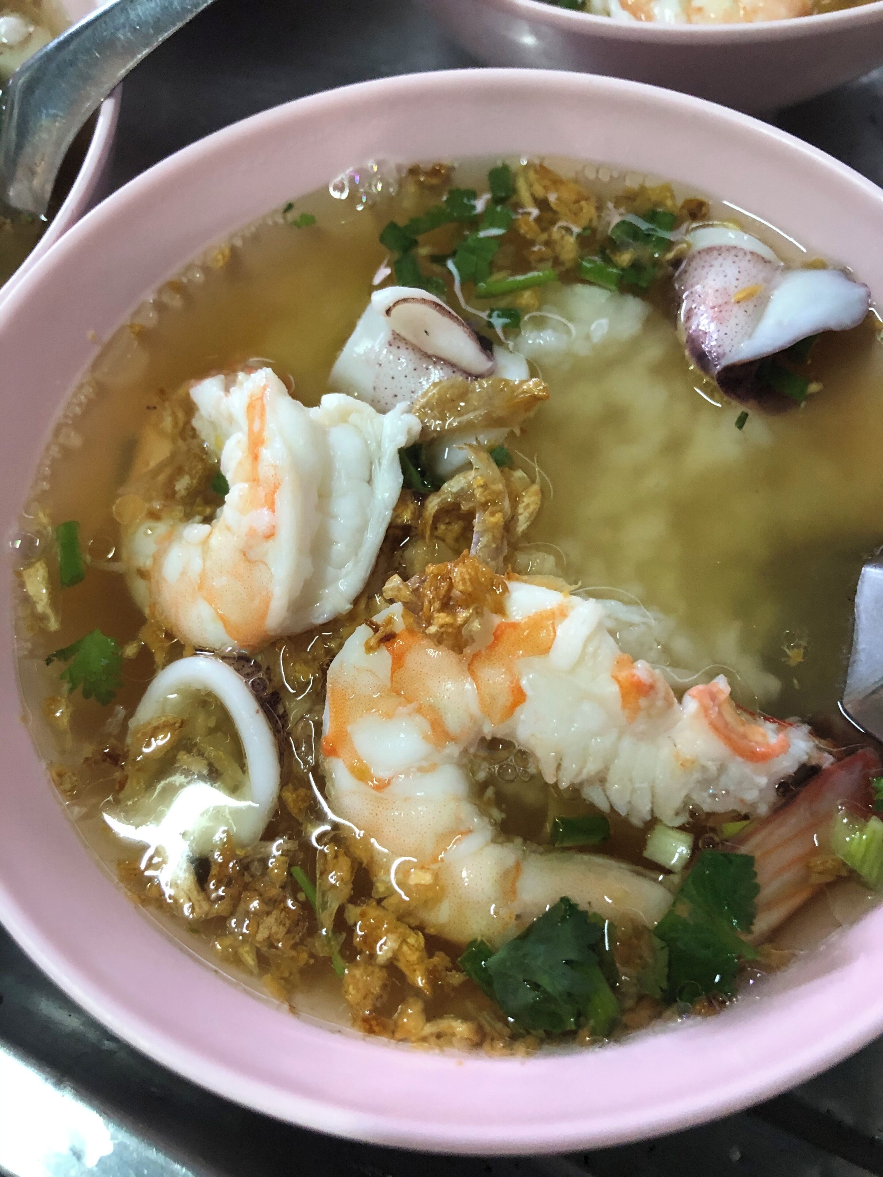 A bowl of soup with shrimp and other ingredients.