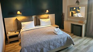 Ein modernes Hotelzimmer mit einem großen Bett, Nachttischen, einem Schminktisch und einem kleinen Schrank.