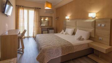 Habitación de hotel con cama, escritorio, silla y televisor en la pared.