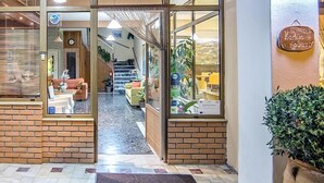 Eine Hotellobby mit Backsteinwand, einem kleinen Tisch mit Topfpflanze und einer Treppe, die in einen oberen Stock führt.
