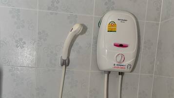 Ducha con cabezal de ducha de mano y controles en la pared.