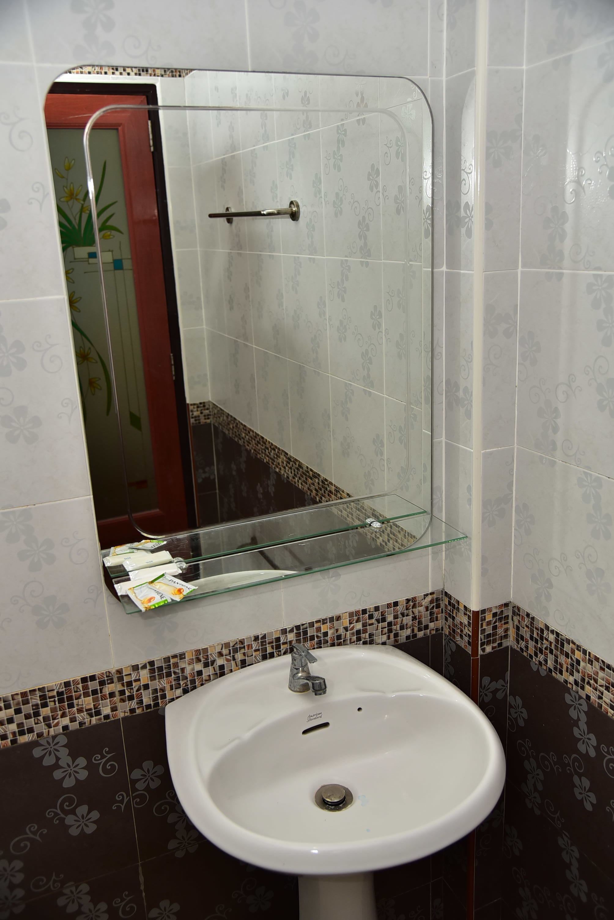 A bathroom with a white sink, a glass shelf, and a mirror.
