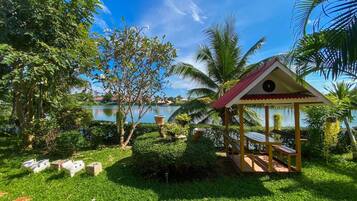 A gazebo with a red roof and a number '4' sign, surrounded by lush greenery and palm trees, with a lake in the background.