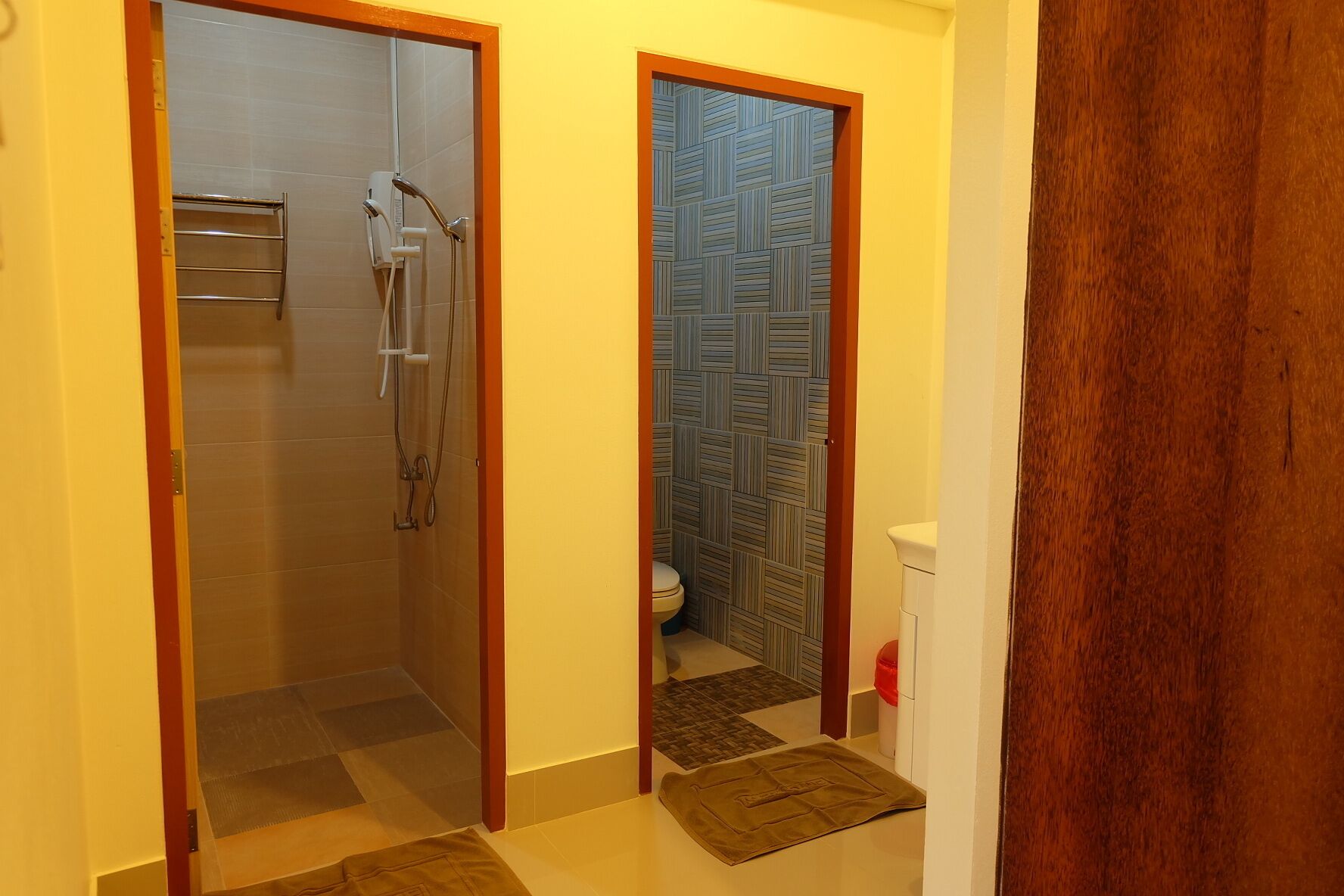 A bathroom with a shower, toilet, and a patterned wall.