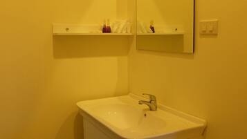 A bathroom with a white sink, a mirror, and a shelf above the sink.