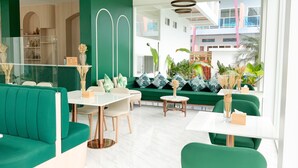 Ein modernes Interieur mit grünen Sofas, einem weißen Tisch und Blick auf ein Gebäude.