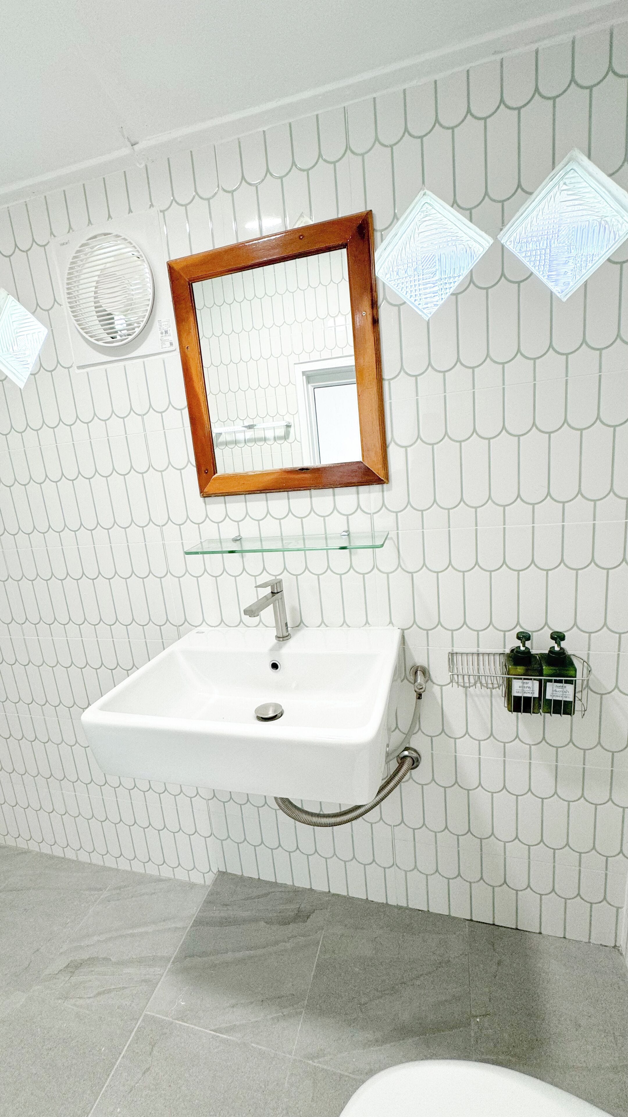 A bathroom with a white sink, a mirror with a wooden frame, and a shower area.