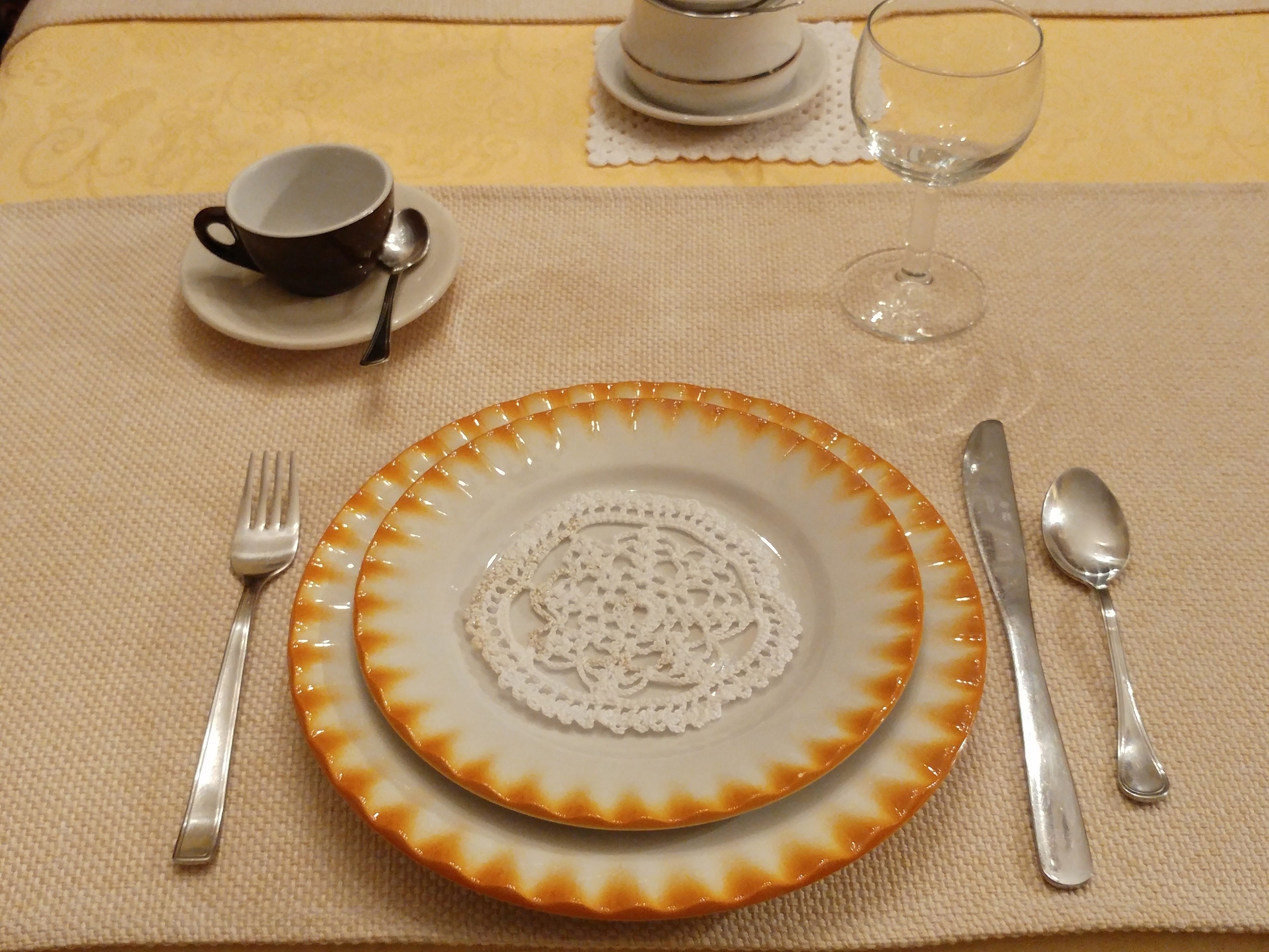 A table set with a plate, fork, knife, and spoon, along with a cup and a glass.
